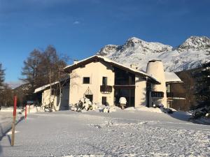 ein Haus im Schnee mit Bergen im Hintergrund in der Unterkunft Chesa Suot Ovas in Sils Maria