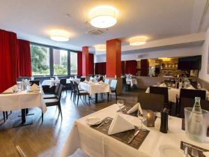 un ristorante con tavoli e sedie bianchi e finestre di DORMERO Hotel Hannover ad Hannover