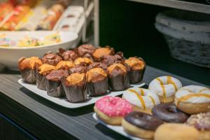 Ein Haufen verschiedener Donuts auf Tellern auf einer Theke. in der Unterkunft Hotel Zeerust Texel in De Koog