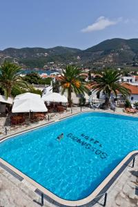 een groot zwembad met palmbomen en parasols bij Dionyssos in Skopelos Town