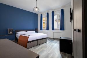 1 Schlafzimmer mit 2 Betten mit blauen Wänden und einem Tisch in der Unterkunft The RomeHello in Rom