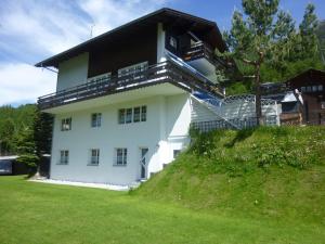 una casa blanca con techo negro en una colina en Haus Edelweiss, en Grächen