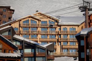 ein großes Gebäude mit Schnee auf dem Boden in der Unterkunft Langley Hôtel Tango in Val Thorens