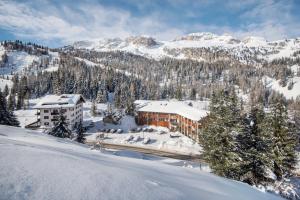 un edificio en la nieve con una montaña en Hotel Garni Elisir, en Arabba