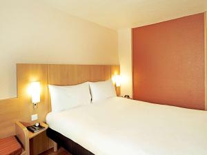 1 dormitorio con 1 cama grande con almohadas blancas en Ibis Barcelona Santa Coloma, en Santa Coloma