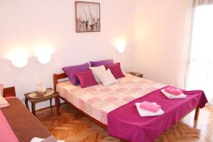 1 dormitorio con 1 cama grande con sábanas rosas y moradas en Guest House Tomanovic, en Herceg-Novi