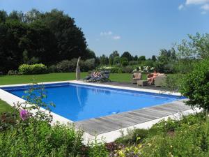 een zwembad in een tuin met mensen op stoelen bij B&B Au Grenier in Gent