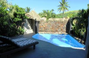 einen Hinterhof mit einem Pool und einer Steinmauer in der Unterkunft Aitutaki Escape in Arutanga