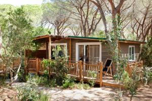 eine Hütte im Wald mit einer Veranda in der Unterkunft Camping Maremma Sans Souci in Castiglione della Pescaia