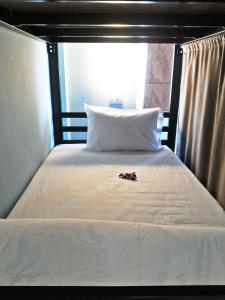 een bed met witte lakens en rode bloemen erop bij One One Hostel Patong in Patong Beach