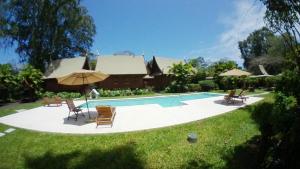 a pool with chairs and umbrellas next to a house at Lanna Ban Hotel in Puerto Viejo