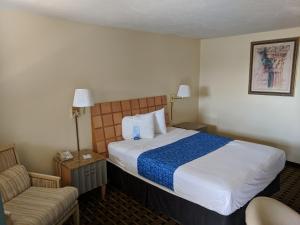 ein Hotelzimmer mit einem Bett und einem Stuhl in der Unterkunft Travelodge by Wyndham Clovis in Clovis