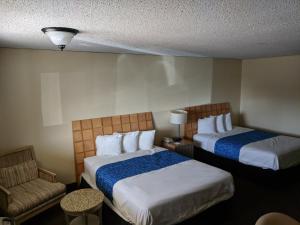 ein Hotelzimmer mit 2 Betten und einem Stuhl in der Unterkunft Travelodge by Wyndham Clovis in Clovis