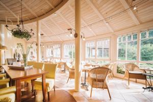 una sala da pranzo con tavolo, sedie e finestre di Appartementhaus Silvia a Bad Füssing