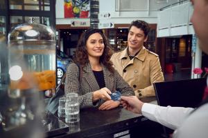 Een man die een vrouw een mobieltje geeft in een bar. bij WestCord Art Hotel Amsterdam 3 stars in Amsterdam