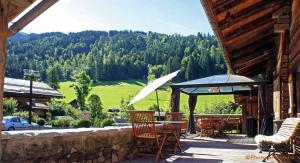 um pátio com uma mesa, cadeiras e um guarda-sol em Chalet le 1791 em La Clusaz