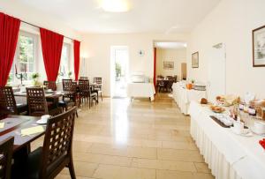 a restaurant with tables and chairs and red curtains at Hotel Biederstein am Englischen Garten in Munich