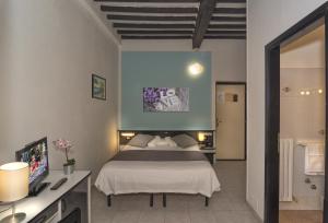 a bedroom with a bed and a desk with a television at Hotel Amalfitana in Pisa