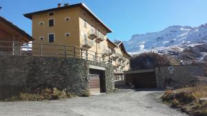 a large yellow building with a garage next to a mountain at Residence Redicervinia in Breuil-Cervinia