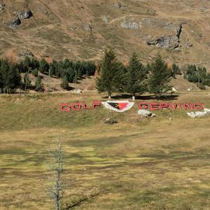 a sign in a field with a mountain in the background at Residence Redicervinia in Breuil-Cervinia