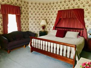 1 dormitorio con 1 cama, 1 silla y 1 sofá en Rabbit Creek Bed & Breakfast, en Versailles