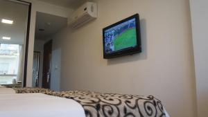 a tv hanging on a wall in a bedroom at Palm Beach Plaza Hotel in Montevideo