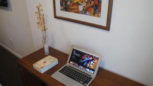 a laptop computer sitting on a wooden desk with a vase at Palm Beach Plaza Hotel in Montevideo