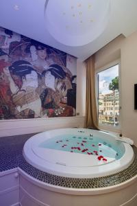 un bagno con una grande vasca da bagno con un murale di Torre Argentina Relais - Residenze di Charme a Roma