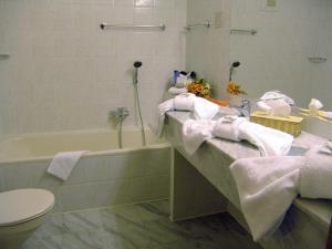 a bathroom with a sink and a tub and towels at Oder-Hotel in Schwedt