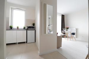 a kitchen with white cabinets and a window and a table at Romantic Sky Apartment- 15th floor in Kraków