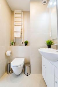 a white bathroom with a toilet and a sink at Romantic Sky Apartment- 15th floor in Kraków