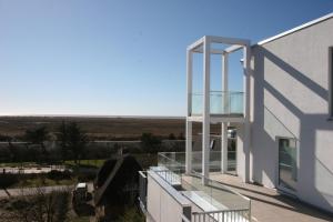 een wit gebouw met een glazen balkon met uitzicht bij Parkhotel Residenz in Sankt Peter-Ording