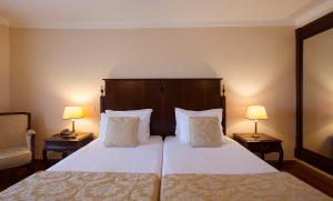 a hotel room with a large bed with two lamps at Turim Club Azeitao Hotel in Setúbal