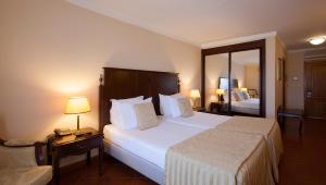 a hotel room with a large bed and a mirror at Turim Club Azeitao Hotel in Setúbal