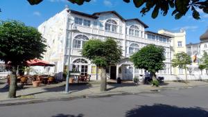 un grand bâtiment blanc avec des arbres devant lui dans l'établissement Hotel Deutsche Flagge, à Binz