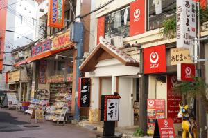 een stadsstraat met veel borden op gebouwen bij Okinawanoyado Ajimaa Makishi in Naha