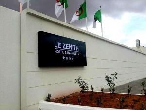 un cartello sul lato di un edificio con bandiere di Le Zenith Hotel Oran a Orano