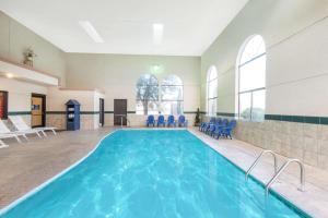 - une piscine dans une pièce avec des chaises bleues dans l'établissement Days Inn by Wyndham Carlsbad, à Carlsbad