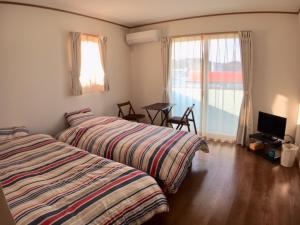 una camera con due letti, un tavolo e una finestra di Sea Side Hostel Light House a Onomichi