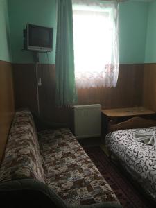 Cette chambre comprend 2 lits et une télévision murale. dans l'établissement Садиба Достаток, à Kolomya