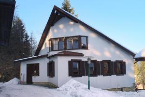 ein weißes Haus mit schwarzen Fenstern im Schnee in der Unterkunft Chalupy Na Rališce in Horní Bečva