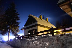 ein Haus voller Schnee in der Nacht mit einem Zaun in der Unterkunft Chalupy Na Rališce in Horní Bečva