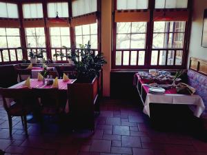 una sala da pranzo con tavoli, sedie e finestre di Guest House Arvaj a Kranj