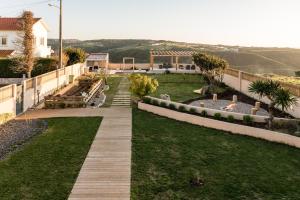 - deux vues sur un jardin avec une passerelle en bois dans l'établissement Eco Soul Ericeira Guesthouse - Adults Only, à Ericeira