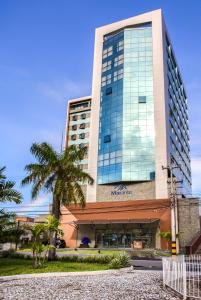 un grand bâtiment avec un palmier devant lui dans l'établissement Marante Executive Hotel, à Récife