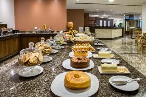 une table avec des gâteaux et des beignets sur un comptoir dans l'établissement Marante Executive Hotel, à Récife