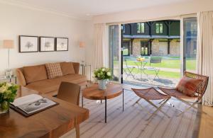 a living room with a couch and a table and chairs at Coworth Park - Dorchester Collection in Ascot