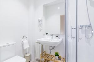 a white bathroom with a sink and a shower at Pensión Buenpas in Donostia-San Sebastián