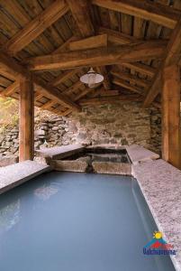 uma piscina num edifício com tecto de madeira em Foresteria B&B Vecchiascuola Pianazzola em Chiavenna