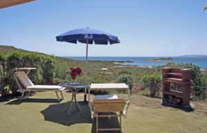 een tafel en stoelen met een parasol en een grill bij Residence Baia Salinedda in San Teodoro